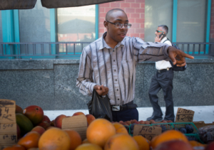 Teenage boy pointing to a product at a produce outdoor market stand